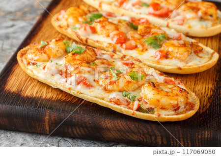 Shrimp Scampi Garlic Bread sandwiches with mozzarella, tomatoes and parsley closeup on the wooden board. Horizontal 117069080