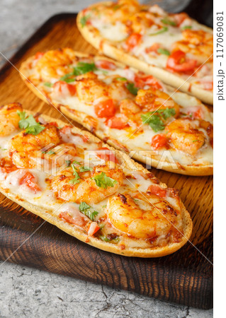 Cheesy Shrimp Garlic Bread with herbs and tomato closeup on the wooden board. Vertical 117069081