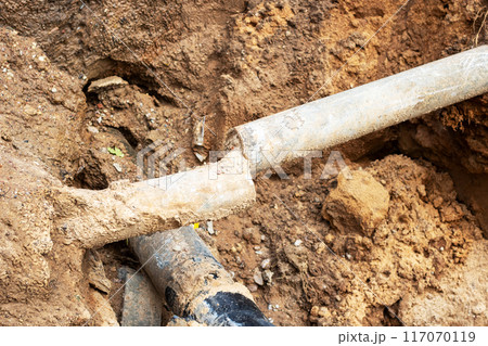 A broken pipe is currently lying in the dirt, waiting to be fixed 117070119