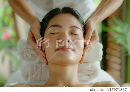 Young woman with eyes closed receiving Thai neck massage peaceful spa stylish decor 117071887
