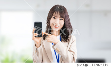 スマートフォンを指差す笑顔の日本人ビジネスウーマン 117073119