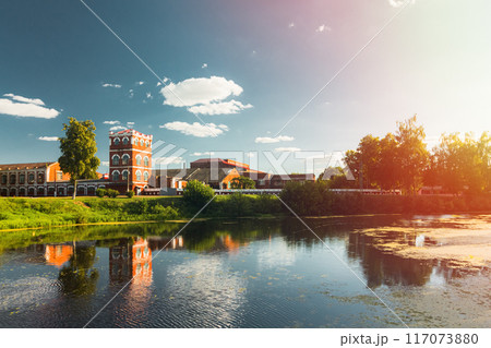 Peaceful and picturesque reflection of a serene river showcasing scenic buildings and lush greenery Peaceful and picturesque reflection of a serene river showcasing scenic buildings and lush greenery 117073880