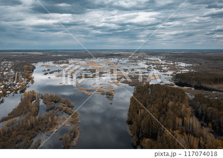 A stunning aerial view of the serene marshlands winding waterways lies under a dramatic, cloudy sky 117074018