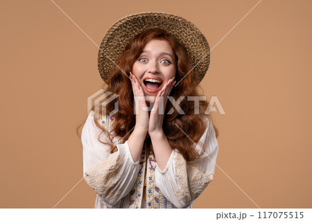 Surprised woman, she expresses WOW, cant believe. Impressed lady trying to get attention. Concept of sales, profitable offer. Excited ginger girl on beige background 117075515