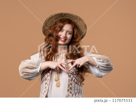 Smiling ginger woman showing sign of shape heart. Positive lady on beige. Love. Women health, volunteering, charity donation, gratitude symbol, flirting concept Smiling ginger woman showing sign of shape heart. Positive lady on beige. Love. Women health, volunteering, charity donation, gratitude symbol, flirting concept 117075531