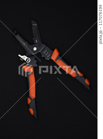 Insulation puller or stripper is an electrical installation tool on a black background. Insulation puller or stripper is an electrical installation tool on a black background. 117076199
