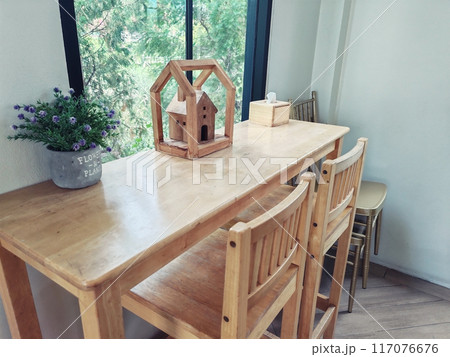 Wooden handcraft home on wood table and chairs by window Wooden handcraft home on wood table and chairs by window 117076676