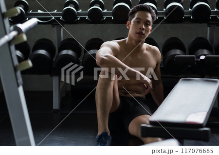 Portrait of handsome Asian man break after dumbbell workout in gym 117076685