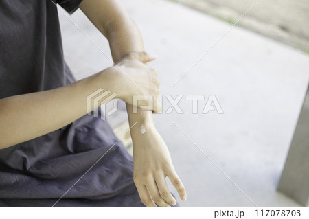 公園で腕に日焼け止めクリームを塗る女性 117078703