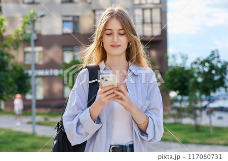 Walking young female using smartphone, modern city background 117080731