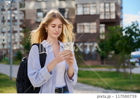 Walking young female using smartphone, modern city background Walking young female using smartphone, modern city background 117080739