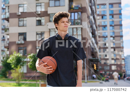 Young male with backpack basketball ball walking outdoors, modern city Young male with backpack basketball ball walking outdoors, modern city 117080742