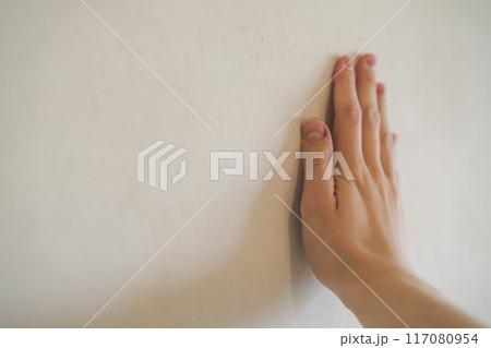 closeup young man hand touching plastered wall closeup young man hand touching plastered wall 117080954