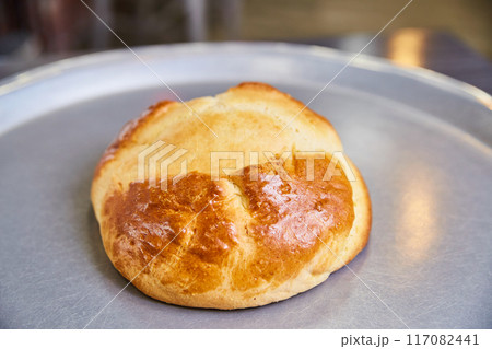 Golden Brioche Bun on Metallic Tray, Close-Up View 117082441