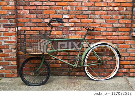 Vintage Green Bicycle Against Rustic Brick Wall in Urban Setting Vintage Green Bicycle Against Rustic Brick Wall in Urban Setting 117082518