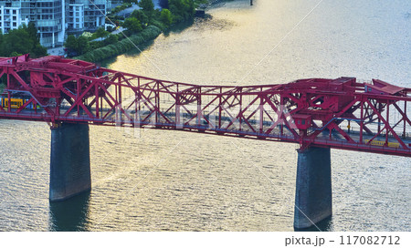Aerial View of Red Truss Bridge with Yellow Tram at Golden Hour 117082712