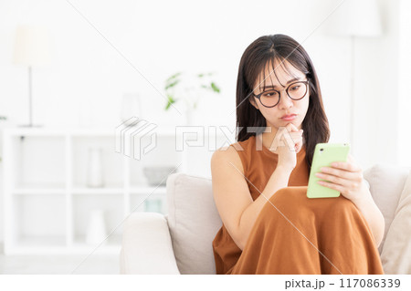 部屋でスマホを見る若い女性 トラブル 部屋でスマホを見る若い女性 トラブル 117086339