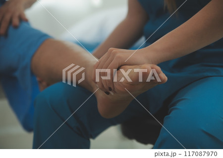 Physical therapists work with patients in close-up clinics. The concept of rehabilitation of physical health, the doctor gives advice to the patient. Ankle problems and muscle injuries 117087970