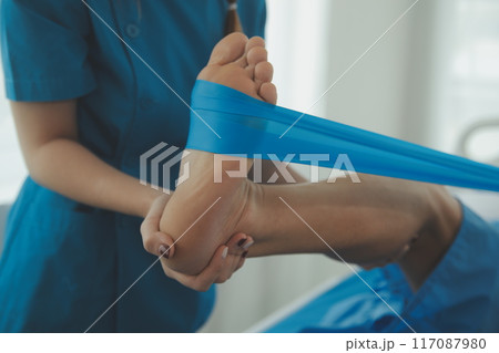 Physical therapists work with patients in close-up clinics. The concept of rehabilitation of physical health, the doctor gives advice to the patient. Ankle problems and muscle injuries 117087980