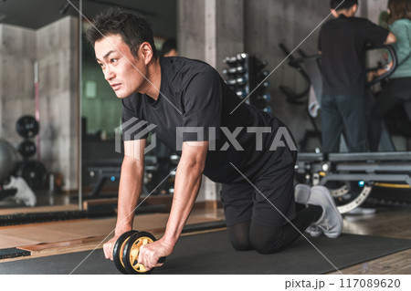 スポーツジムでアブローラーを使い腹筋をトレーニングしているアジア人男性 スポーツジムでアブローラーを使い腹筋をトレーニングしているアジア人男性 117089620