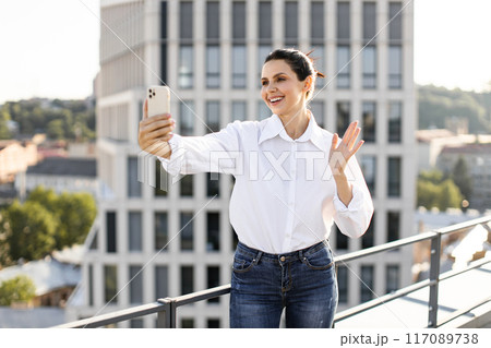Woman taking selfie with smartphone on urban rooftop 117089738