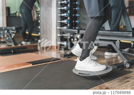 スーツジムでバランスボードに乗って体幹トレーニングする男性の足元 117089898
