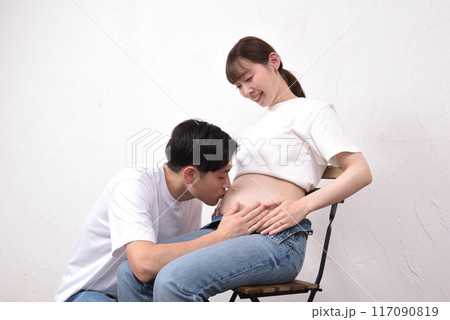 妊娠した妻の大きなお腹にキスする若い夫 117090819