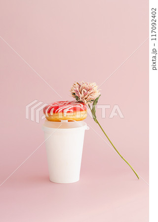 Donut with dried flower and paper coffee cup against pink background. 117092402