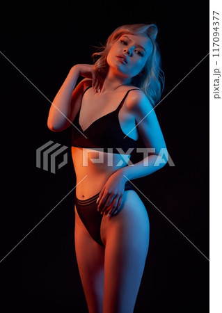 Slim woman in underwear under color light Slim woman in underwear under color light 117094377