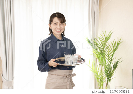 笑顔でお冷を運ぶカフェの女性スタッフ 117095051