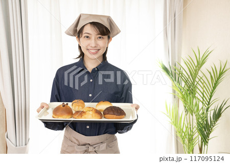 焼きたてのパンを持つベーカリーの女性スタッフ 117095124