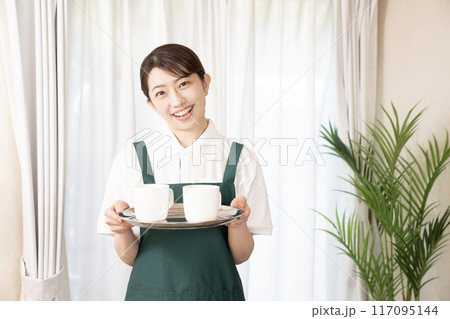 笑顔でコーヒーを運ぶカフェの女性スタッフ 117095144