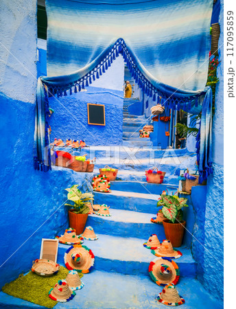 Chefchaouen, Morocco. Blue staircase and wall decorated with colourful flowerpots. 117095859