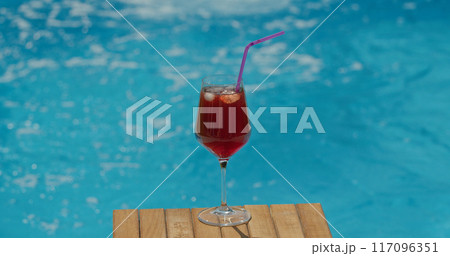 Glass with a cold cocktail set against the pools water surface 117096351