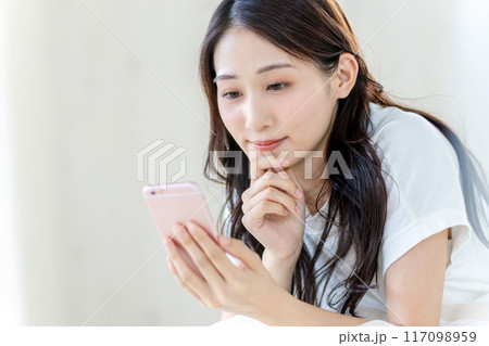 真顔でスマホを見る女性 117098959