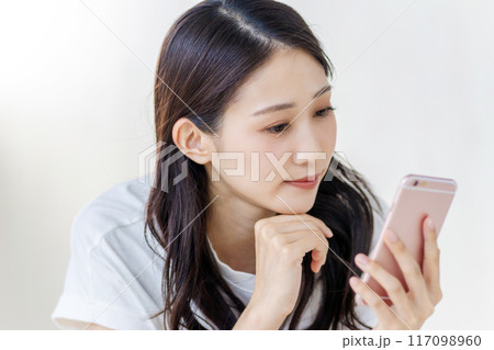 真顔でスマホを見る女性 117098960
