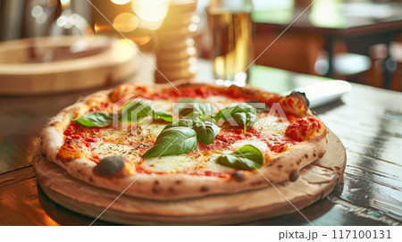Close-up of fresh baked Italian pizza on old rustic wooden table in restaurant background with bokeh 117100131