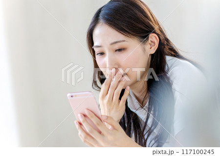 スマホを見て驚く女性 スマホを見て驚く女性 117100245