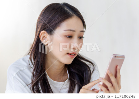 真顔でスマホを見る女性 117100248