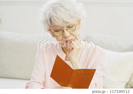 年金手帳を見て悩むシニア女性 117100512
