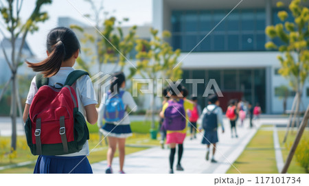 back view of schoolgirl with backpack running to school. 117101734