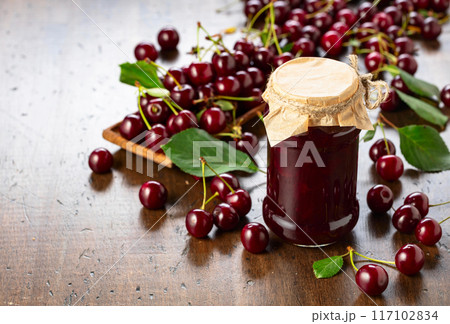 Cherry jam and fresh berries on an old wooden table. Cherry jam and fresh berries on an old wooden table. 117102834