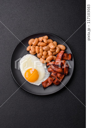 English breakfast with fried eggs, bacon, beans, tomatoes, spices and herbs English breakfast with fried eggs, bacon, beans, tomatoes, spices and herbs 117103083