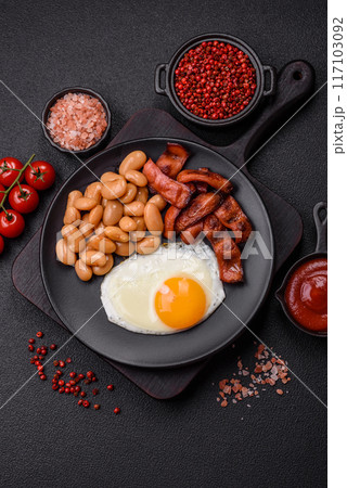 English breakfast with fried eggs, bacon, beans, tomatoes, spices and herbs English breakfast with fried eggs, bacon, beans, tomatoes, spices and herbs 117103092