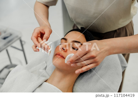 Woman Relaxing During Facial Treatment at Spa in Natural Light Setting 117104419