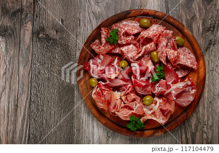 Assortment , sliced meat appetizer, prosciutto, salami and ham, with olives, on a wooden board, breakfast, top view, close-up, no people, 117104479