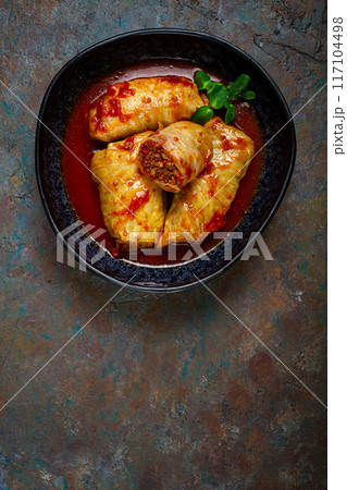 Stuffed cabbage rolls with minced meat, in tomato sauce, top view, without people, in the spotlight. 117104498