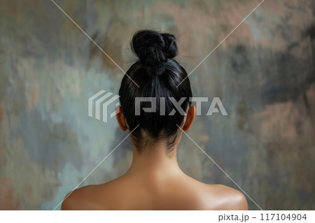Rear view of a woman's top knot hairstyle against an artistic background 117104904