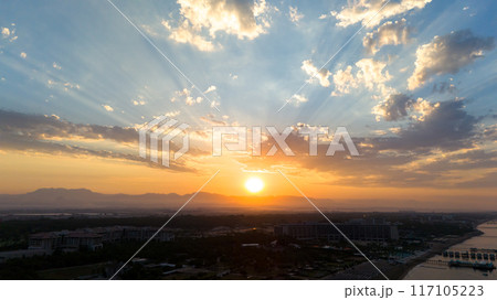 Dramatic sky illuminated by the rising sun over a beautiful sea coast Dramatic sky illuminated by the rising sun over a beautiful sea coast 117105223