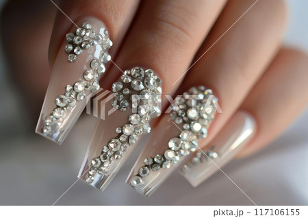 Close-up of elegant hands showing off long, transparent nails adorned with sparkling crystals 117106155